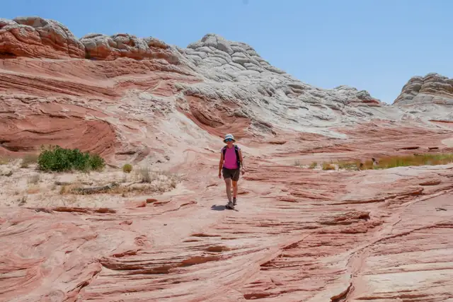 Lone hiker walking across red rock desert terrain