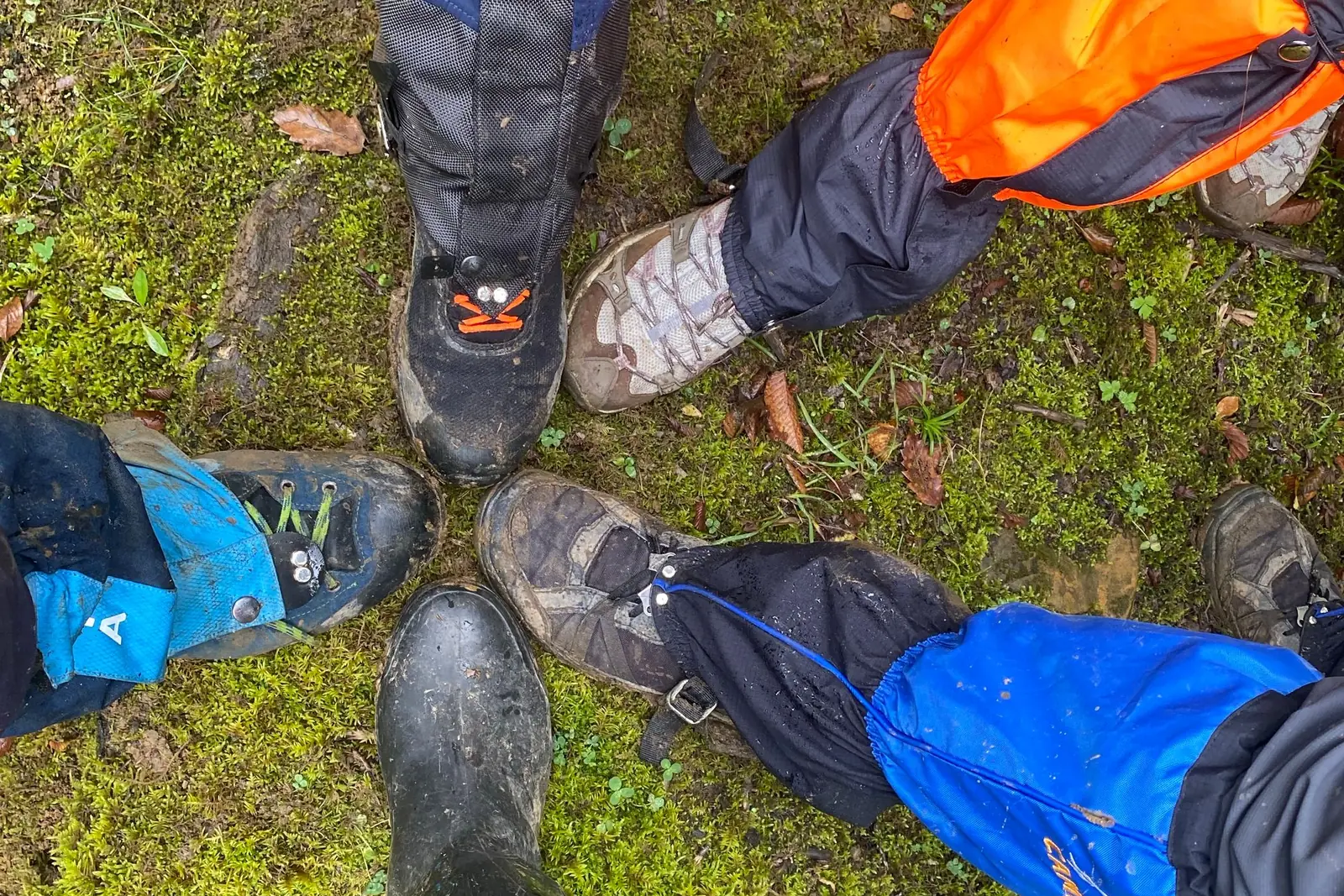 Overhead view of hikers' boots and gaiters gathered on mossy ground