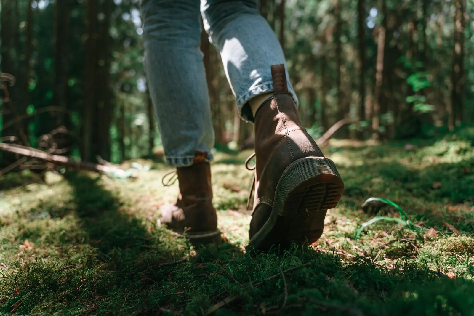 Brown leather boots walking along a sunlit woodland trail