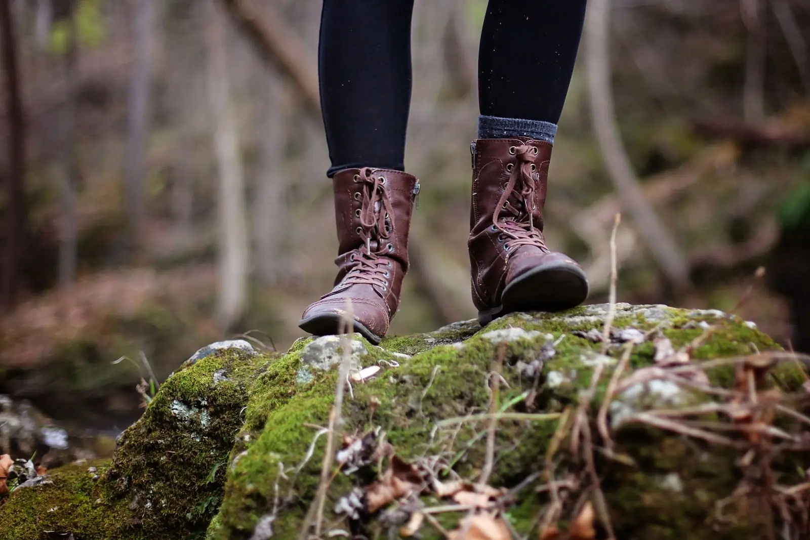 Tall leather boots standing on a mossy rock in a forest